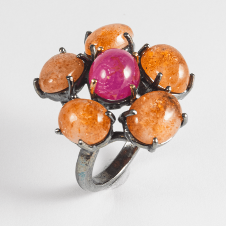 A Handmade Oxidised Sterling Silver, 18ct Yellow Gold, Cabochon Sunstone and Ruby (0.68ct) DAISY RING.  Gold mass 0.83 gms
